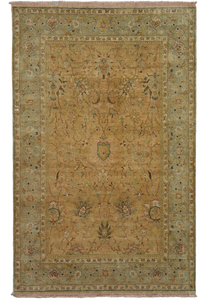 A rectangular vintage-style area rug with a distressed medallion pattern in muted olive green, tan, and beige tones, featuring fringed edges.