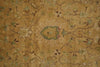 Load image into Gallery viewer, A close-up of an antique-style area rug with a distressed floral pattern in warm tan, beige, muted green, and brown tones.