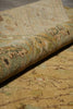 Load image into Gallery viewer, A close-up of a rolled section of an area rug showing its detailed vintage-style floral and botanical pattern in muted beige, sage green, and brown tones.