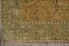 Load image into Gallery viewer, A close-up of an ornate area rug showing its corner, border, and fringe. The rug features a muted sage green and ochre yellow base with intricate floral motifs and traditional patterns.