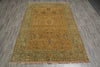 Load image into Gallery viewer, A rectangular vintage-style area rug with a central medallion and floral motifs, laid flat on a gray wood-look floor. The rug features a warm mustard-yellow center, a muted sage-green border, and dusty pink fringe.