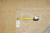 Load image into Gallery viewer, A close-up of a vintage patterned wall hanging or rug corner, showing a beige floral textile with a yellow tape measure and a small white inventory tag attached.