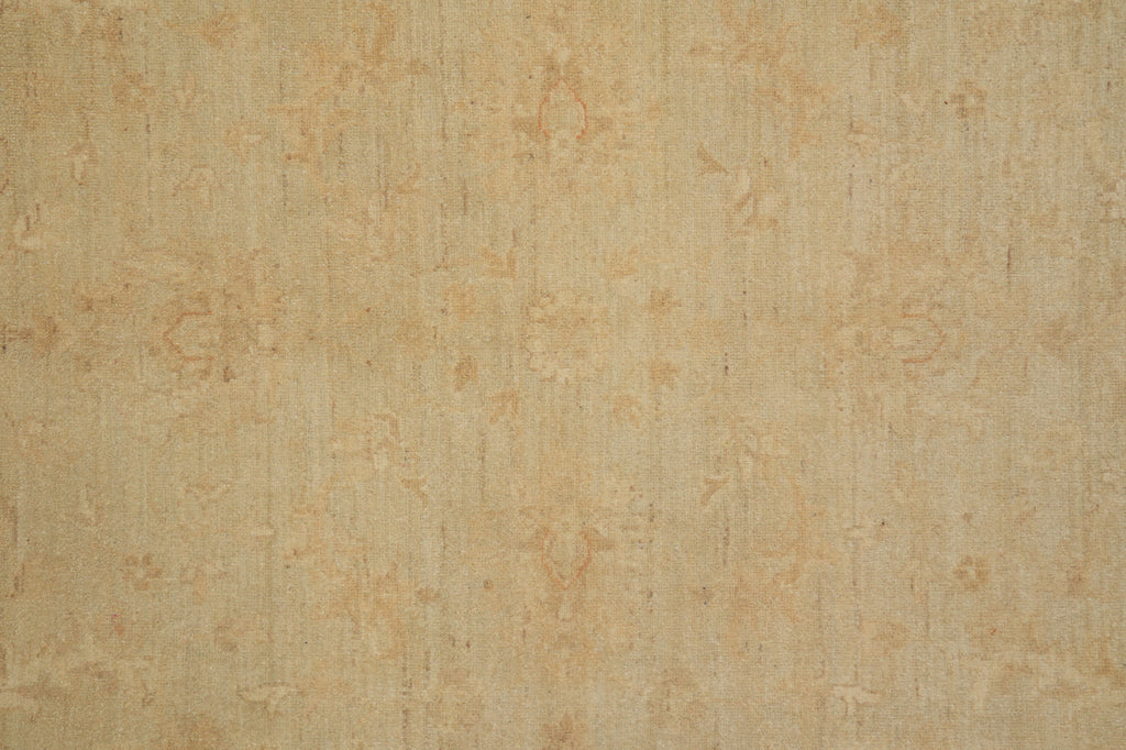 A close-up of a beige fabric or carpet texture with a subtle, faded damask-style pattern in slightly warmer tan and light brown tones.