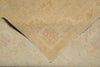 Load image into Gallery viewer, A close-up of a folded beige area rug with a subtle, faded traditional floral pattern and fringed edges.
