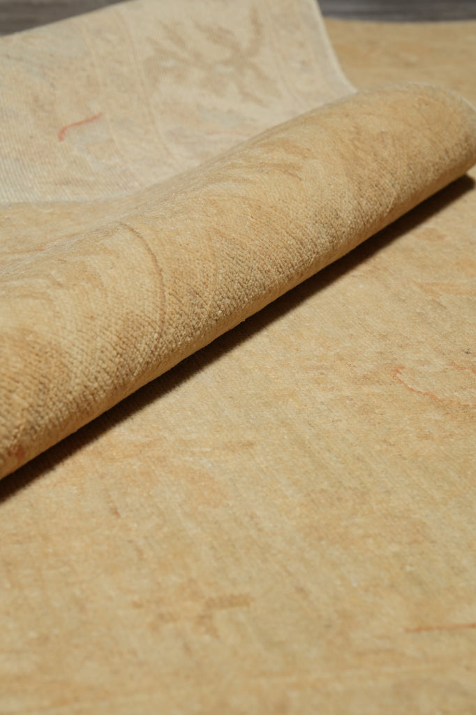 A close-up of a rolled beige fabric or textile laid over a matching flat surface, showing a soft woven texture and subtle tonal pattern.
