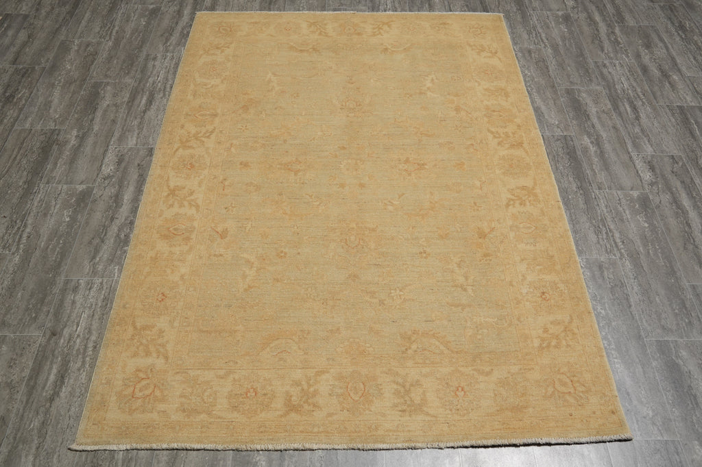 A rectangular area rug in a warm sandy beige color with a subtle faded traditional floral pattern, shown flat on a gray wood-look floor.
