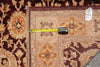 Load image into Gallery viewer, A close-up of an area rug corner with a yellow tape measure laid across it for size reference, and a hanging tag visible on the upper right.