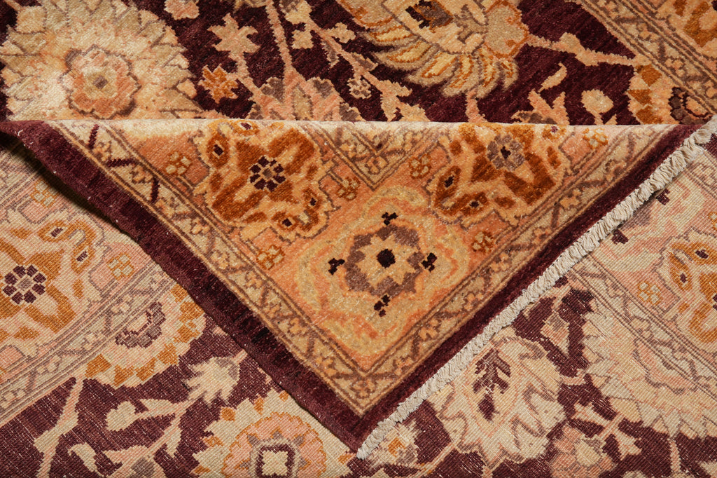 A close-up of a traditional oriental rug showing its detailed floral pattern and corner design in warm tones of beige, brown, and deep burgundy.