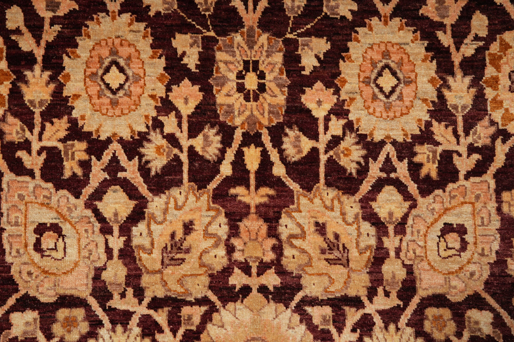 A close-up of a traditional patterned rug with a dark brown background and beige, tan, and muted orange floral and geometric motifs.