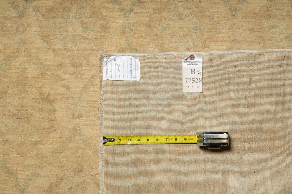 A square area rug with a beige and brown traditional pattern, shown flat on a matching patterned background with a yellow tape measure and inventory tags.
