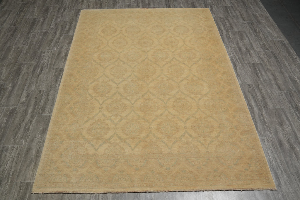 A rectangular area rug with a warm beige and light brown traditional medallion pattern, laid flat on a gray wood-look floor.
