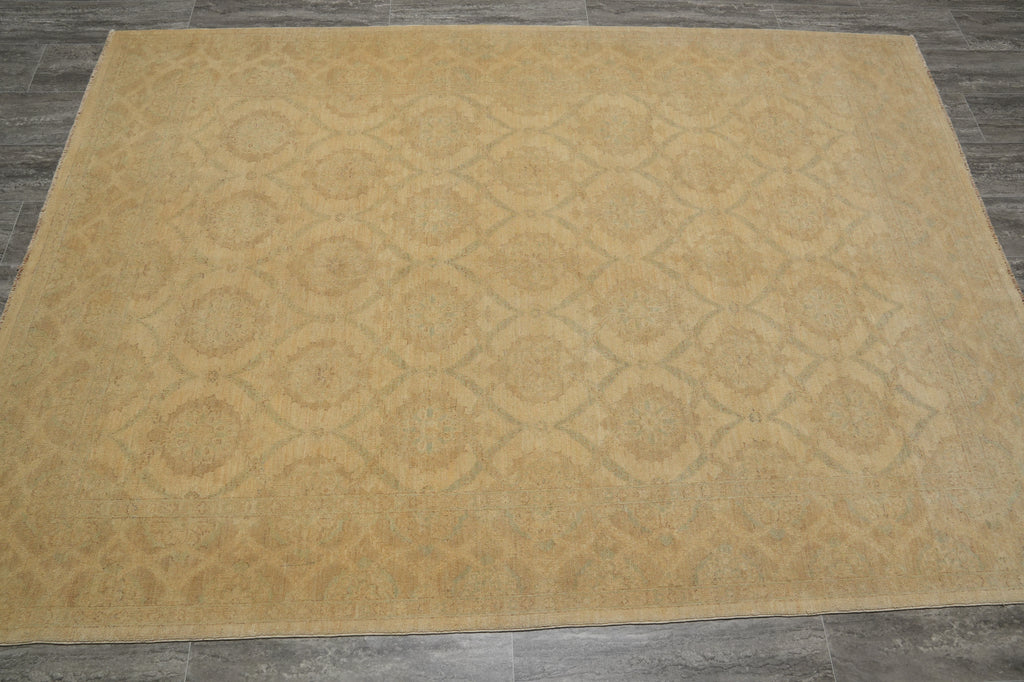 A large rectangular area rug with a beige and light brown geometric trellis pattern, laid out on a dark gray tiled floor.