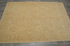 Load image into Gallery viewer, A large rectangular area rug with a beige and light brown geometric trellis pattern, laid out on a dark gray tiled floor.