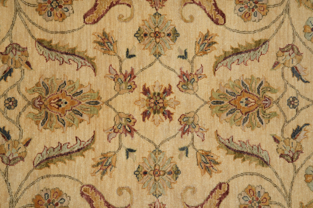 Close-up of a woven textile pattern with a beige background and ornate floral and vine motifs in muted green, rust red, and tan.