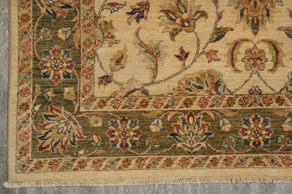 Close-up of a traditional oriental rug corner showing a beige field, olive green border, and floral motifs in muted red, blue, and brown tones.