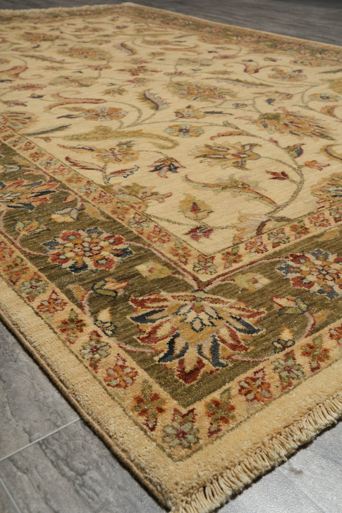 A traditional oriental-style area rug with a beige base and an intricate floral pattern in muted green, rust red, and blue, shown laid out on a gray tiled floor.