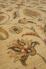 Load image into Gallery viewer, Close-up of a traditional floral area rug with a warm beige background and multicolored embroidered or woven floral motifs in muted orange, green, blue, and brown tones.