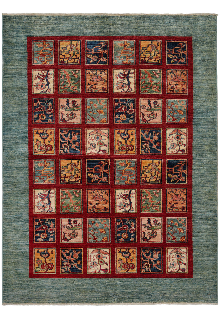 An area rug with a textured slate blue-green border and a central grid of square panels in red, beige, and navy, each containing traditional oriental motifs.
