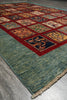 Load image into Gallery viewer, A traditional multi-panel area rug with a textured teal-green border and a central grid of colorful square motifs in red, blue, orange, and beige, laid out on a gray concrete floor.