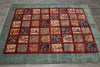 Load image into Gallery viewer, A large rectangular area rug with a teal-blue border and a grid of small multicolored medallion panels, photographed from above on a gray wood floor.