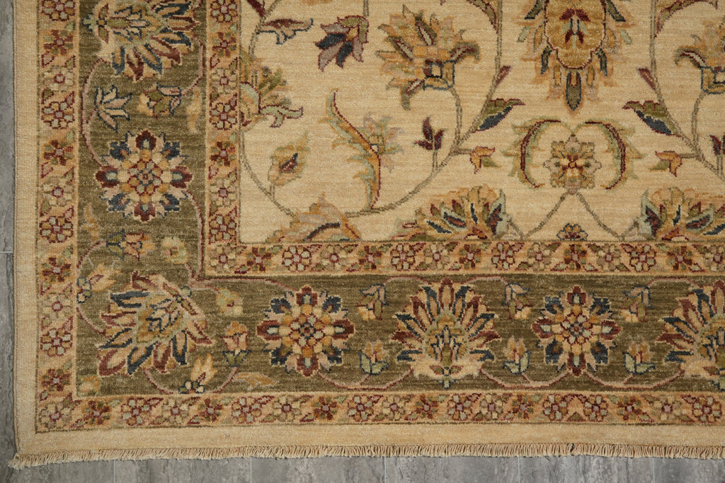 A close-up of a traditional oriental rug showing its corner, featuring a beige field with a green border and floral motifs in muted red, blue, and brown.