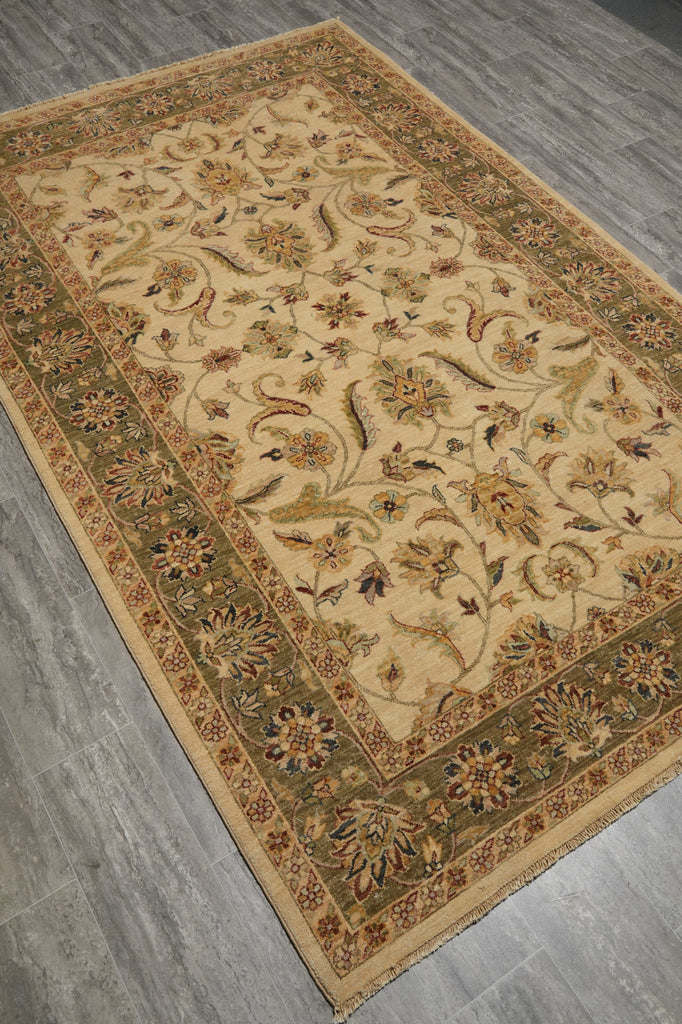 An ornate rectangular area rug with a beige center and detailed floral motifs, displayed on a gray wood-look floor.