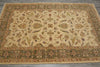 Load image into Gallery viewer, An ornate rectangular area rug with a traditional floral and vine pattern, featuring a cream center field and a detailed olive green border, laid out on a gray tiled floor.