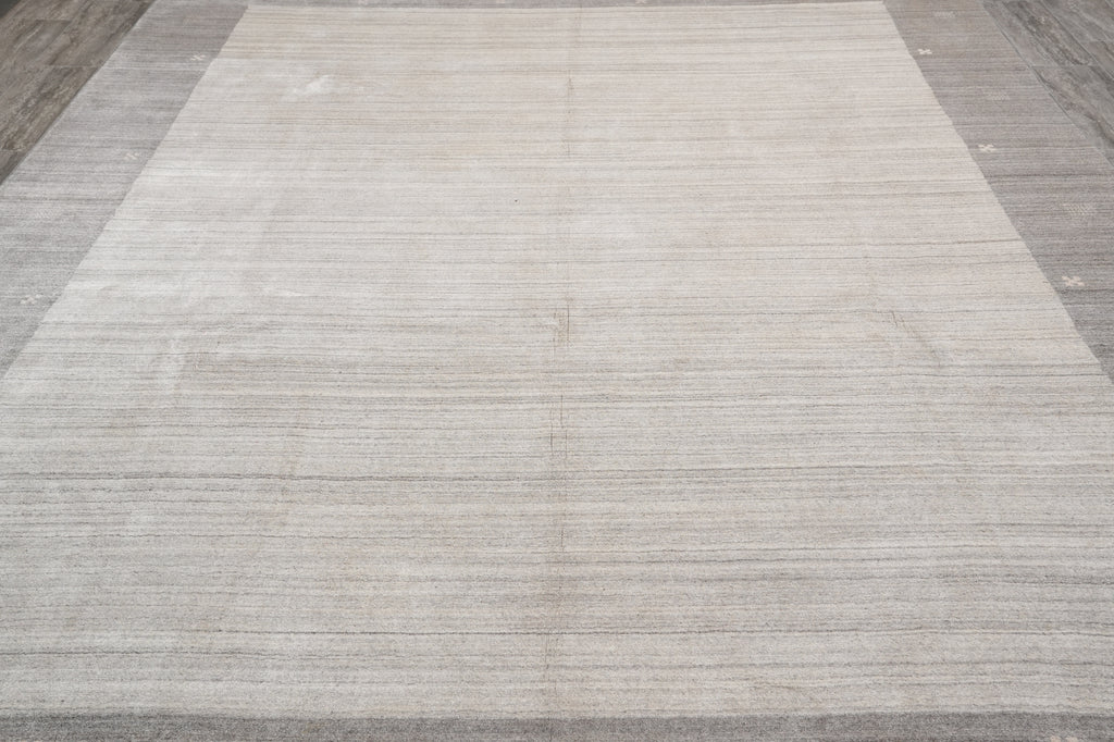 A large rectangular area rug with a textured, heathered light gray and beige surface, shown laid out on a dark wood floor.