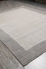 Load image into Gallery viewer, A rectangular area rug with a wide light beige center and a contrasting medium gray border, shown laid out on a gray wood-look floor.