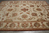 Load image into Gallery viewer, An ornate traditional area rug with a cream background and intricate floral motifs in rust red, olive green, and tan, laid out on a gray tiled floor.