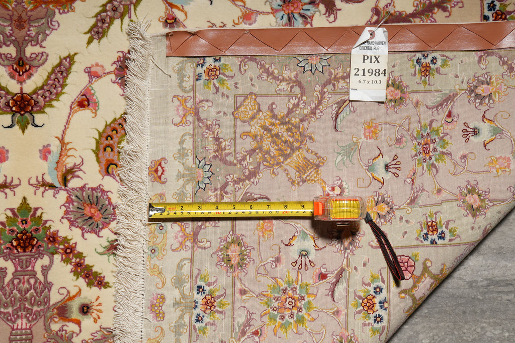 Back of the 6.7 x 10.3 Persian Tabriz rug being measured with a tape measure, showing the hand-woven oriental rug hang tag labeled PIX-21984