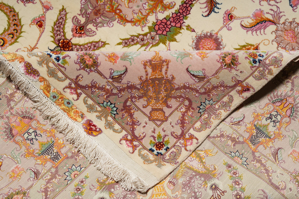 Folded corner of the Persian Tabriz rug showing dense hand-knotted pile on the front and back, with fringe and urn medallion motif