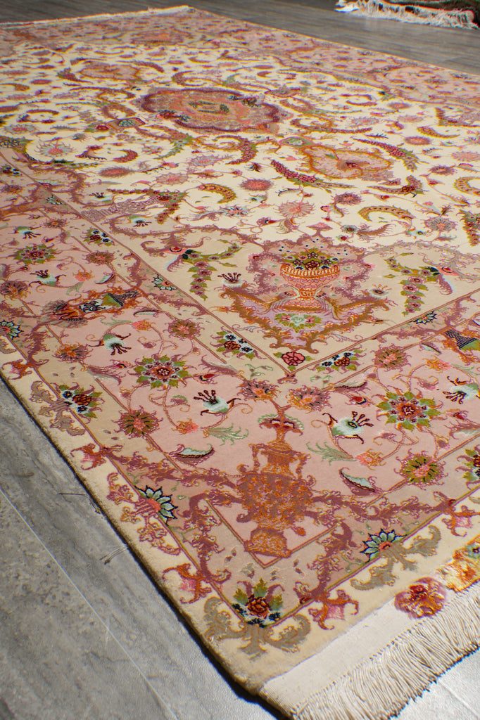 Corner detail of the 6.7 x 10.3 Persian Tabriz rug showing the ivory field, urn and floral motifs, and rose-pink border