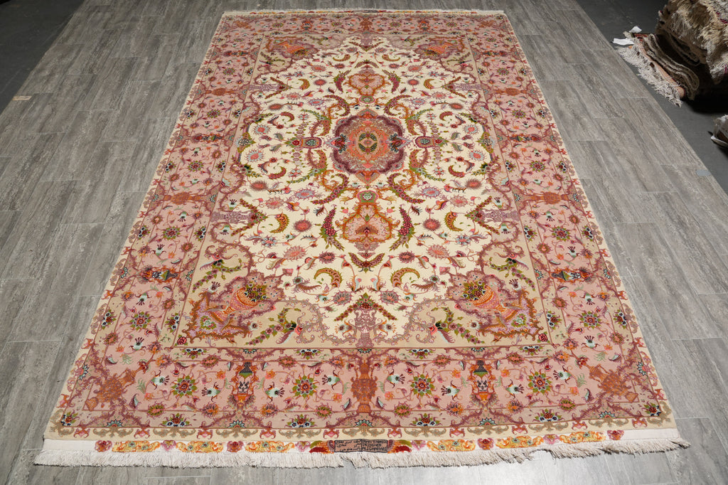 Full view of the 6.7 x 10.3 hand-knotted Persian Tabriz rug laid flat, showing the ivory field, floral border, and woven signature panel