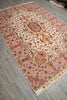 Load image into Gallery viewer, 6.7 x 10.3 Persian Tabriz rug on a gray wood-look floor, showing the ivory center medallion with pink border and orange, green, and blue floral accents