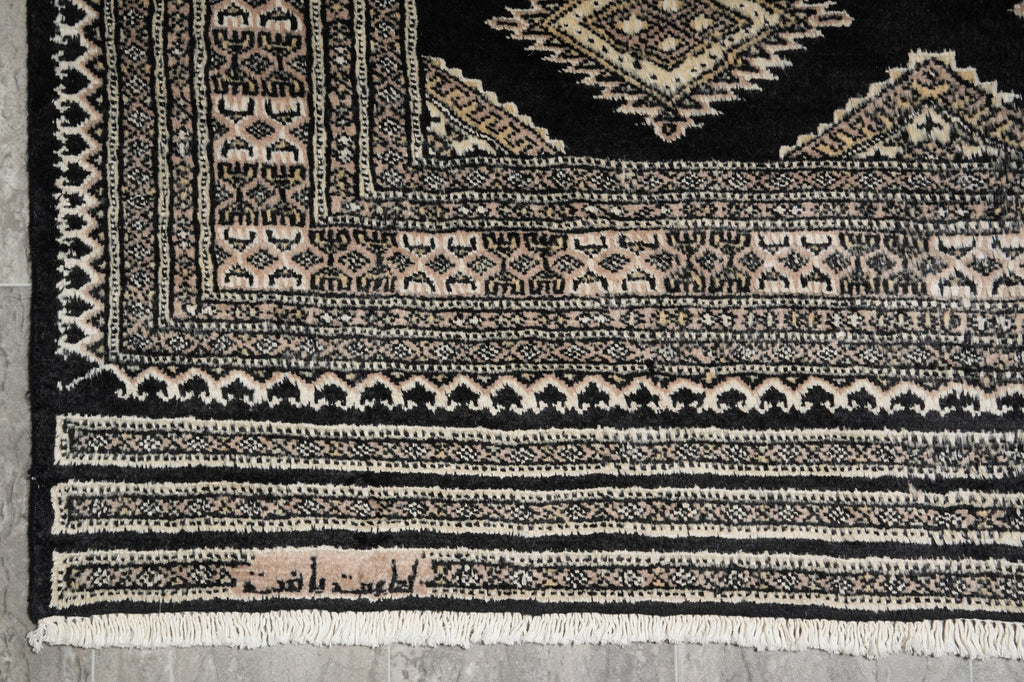 Close-up of a patterned rug with geometric designs on a gray floor.