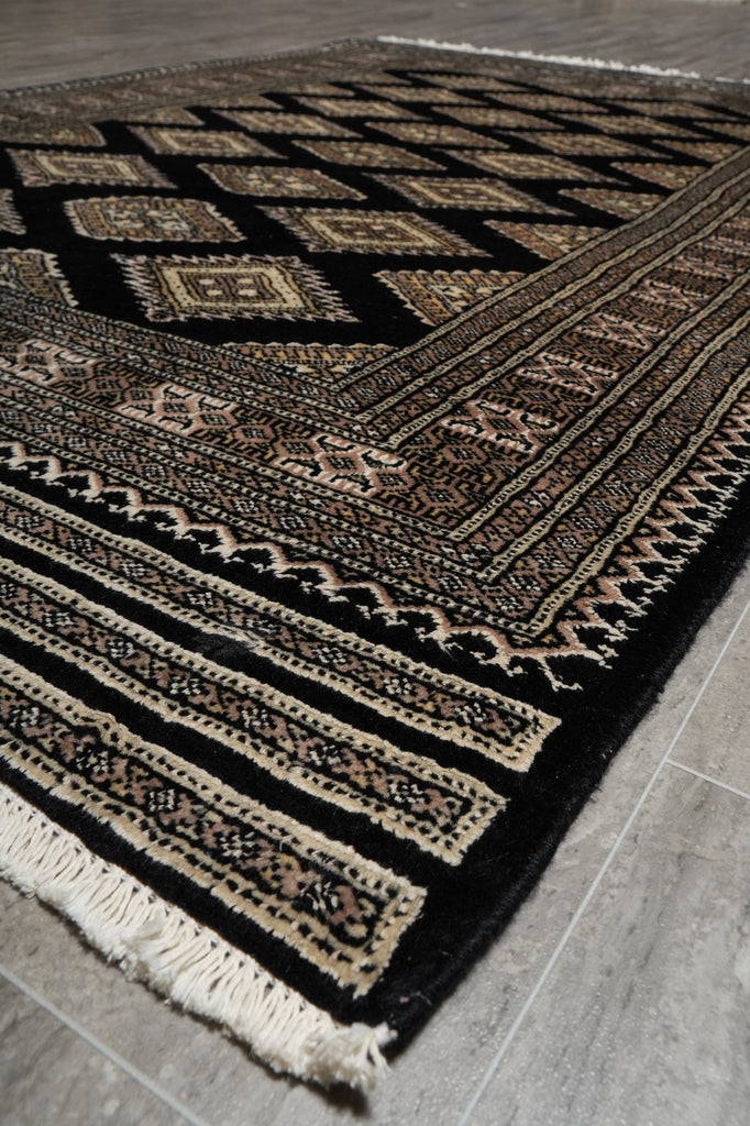 Patterned black and beige rug on a wooden floor