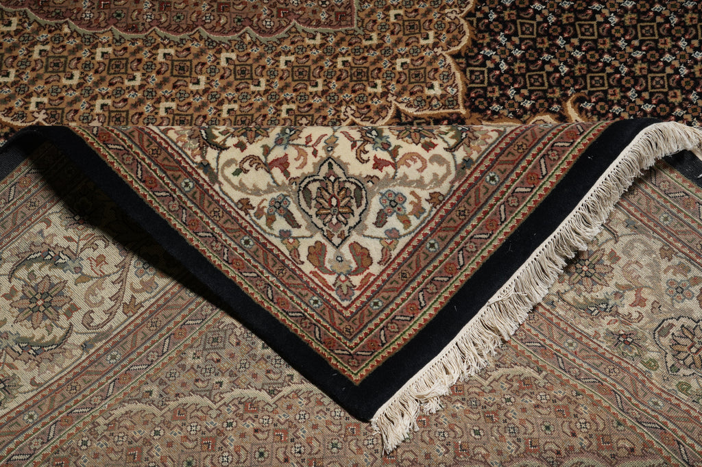 Close-up of a patterned rug with intricate designs and fringes.
