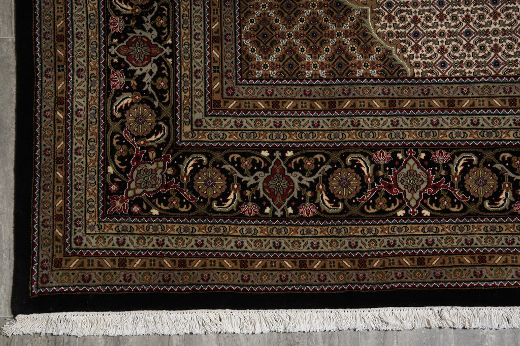 Close-up of a patterned rug with intricate designs on a concrete floor.