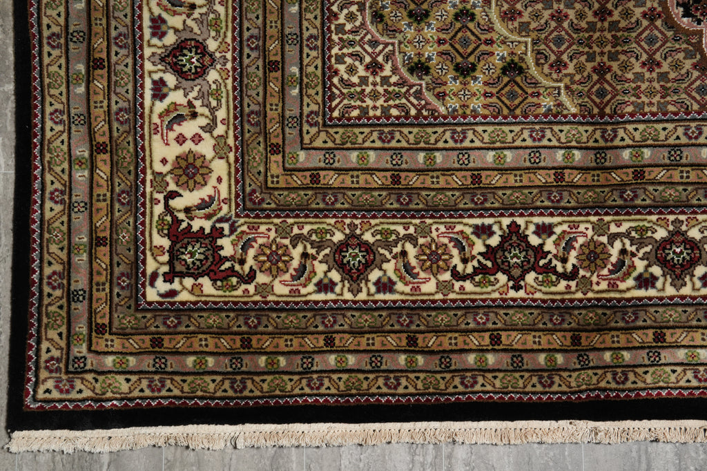 Close-up of a patterned rug with intricate designs on a concrete floor.