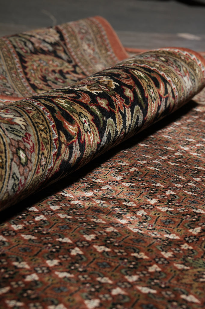 Roll of patterned rug with intricate designs on a dark surface