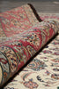 Load image into Gallery viewer, Rolling up a patterned rug on a wooden floor