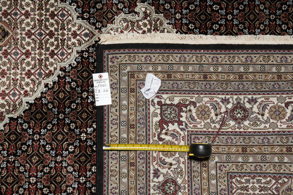 Patterned rug with a measuring tape on top, showing measurements.