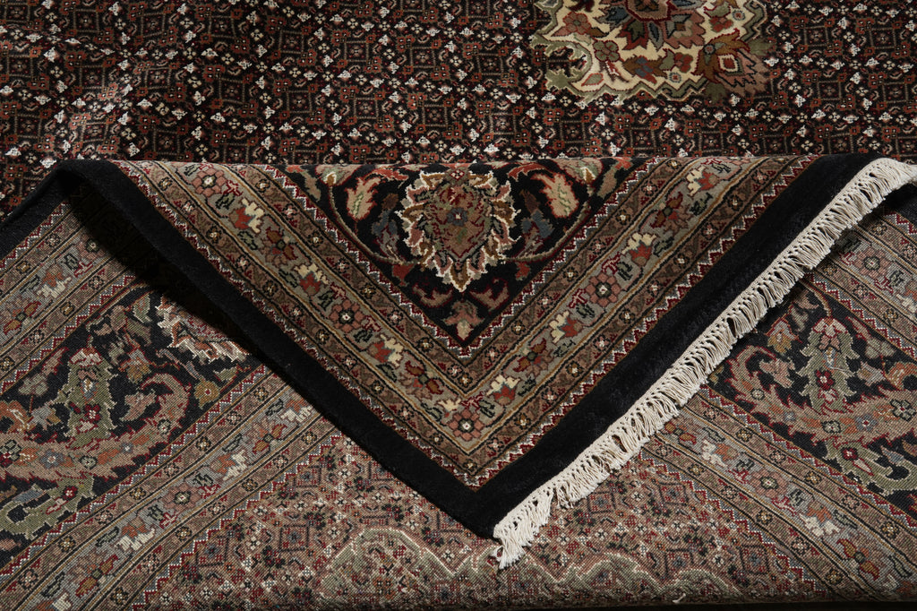 Close-up of a patterned rug with intricate designs and fringes.