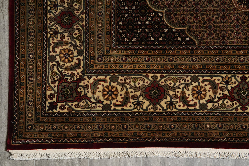 Close-up of an intricately designed rug with detailed patterns on a gray floor.