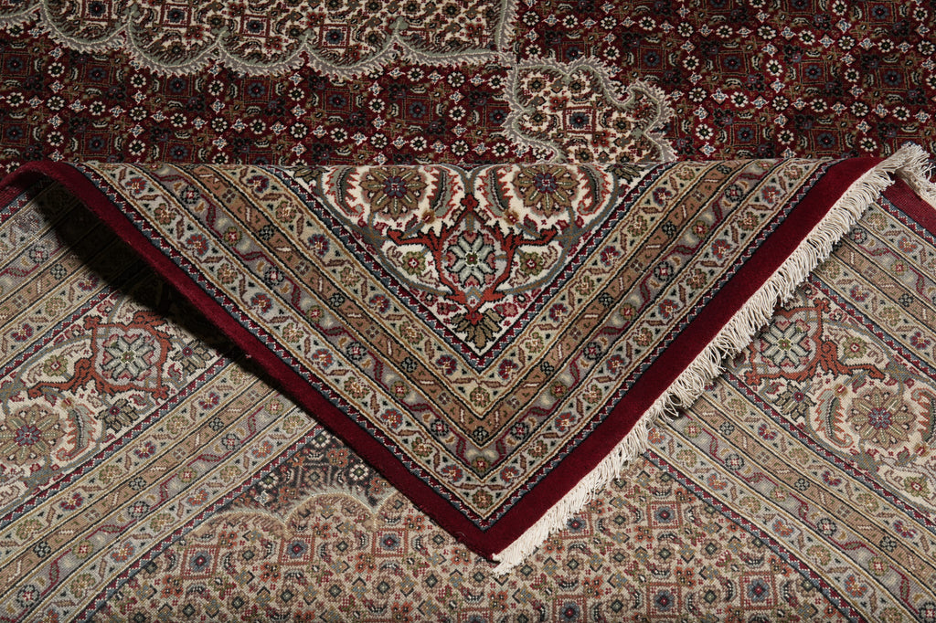 Close-up of a patterned rug with intricate designs and red border.