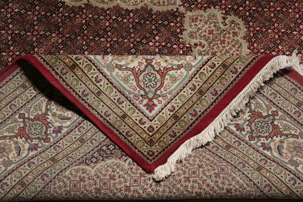 Close-up of a patterned rug with red border and intricate design.