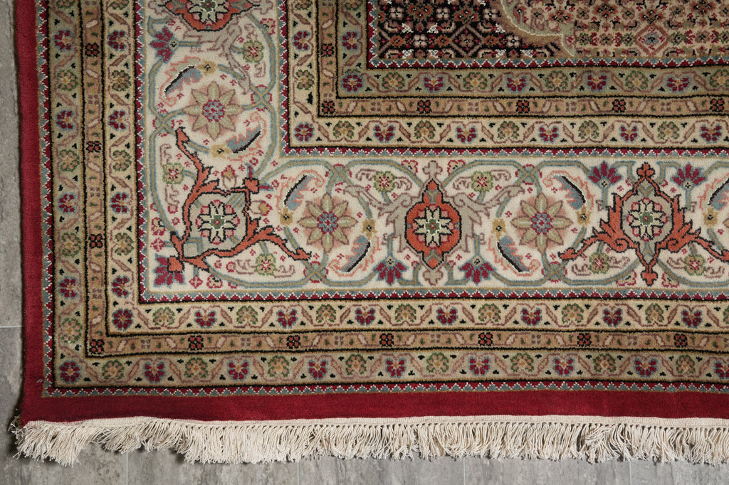 Close-up of a patterned rug with intricate designs on a concrete floor.