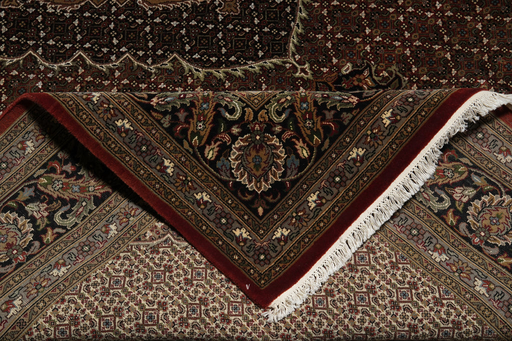Close-up of a patterned rug with intricate designs and fringes.