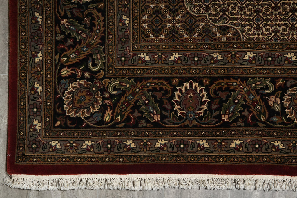 Close-up of an ornate rug with intricate patterns on a gray floor.